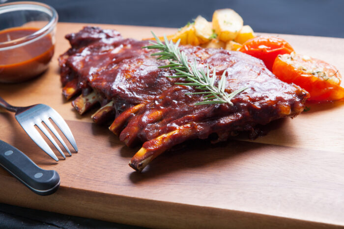 Pork,spareribs,with,tomato,and,fried,potatoes,on,wooden,plate